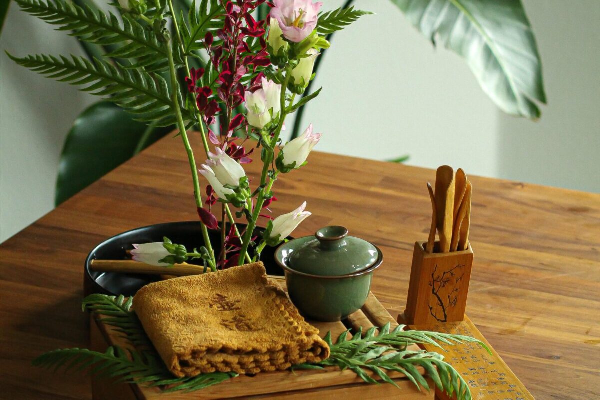 A flower arrangement with a cup, a towel and some tools